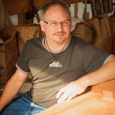 Photo of Aaron Nelson-Moody, a light-skinned man with dark, greying hair, wearing jeans and a t-shirt.