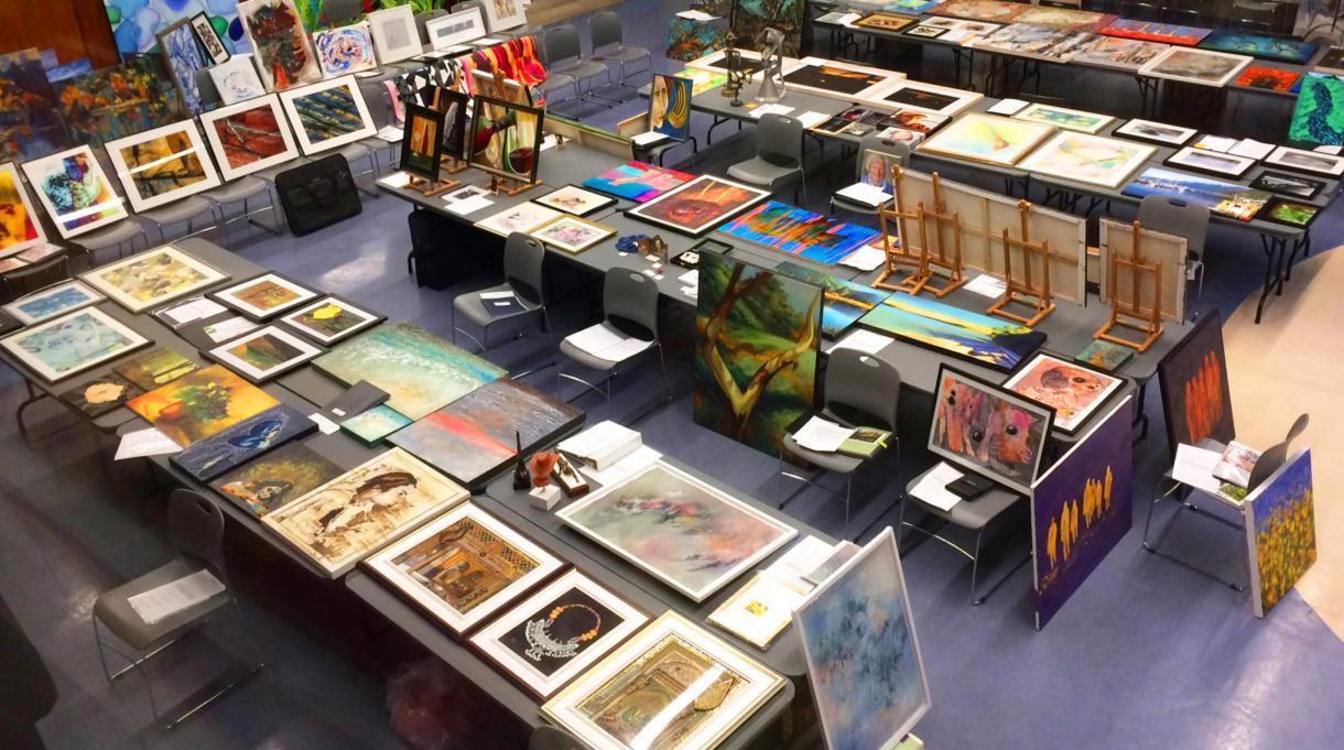 Paintings laid out on tables and leaning on the walls